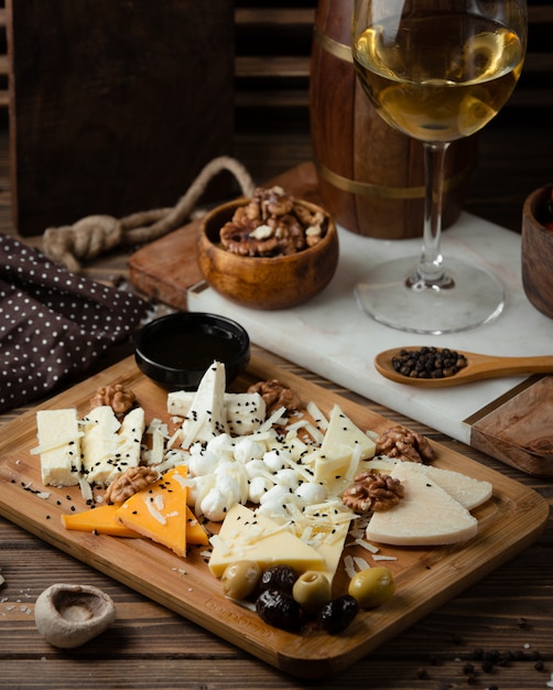 Free photo cheese plate on wooden board with white wine