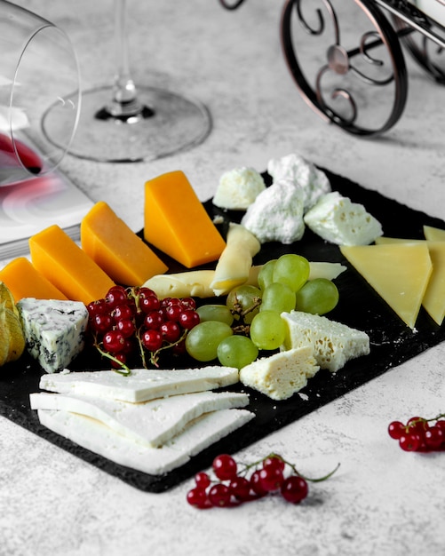 Free photo cheese platter with cheddar blue goat and white cheese parmesan and grape