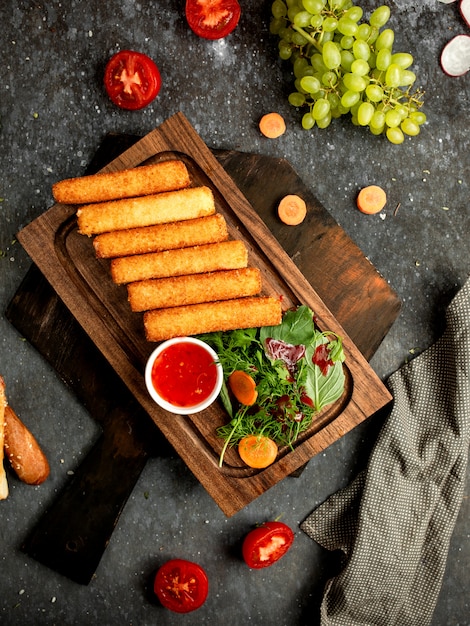 Cheese sticks in batter on a wooden board