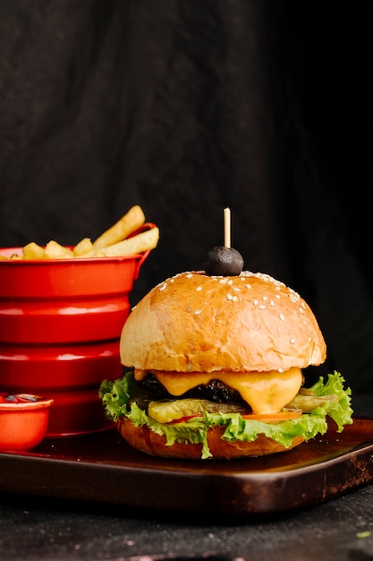 Cheeseburger in bread bun with french fries in red container.