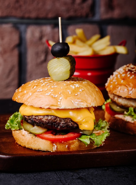 Cheeseburger in bread bun with olives on the top.