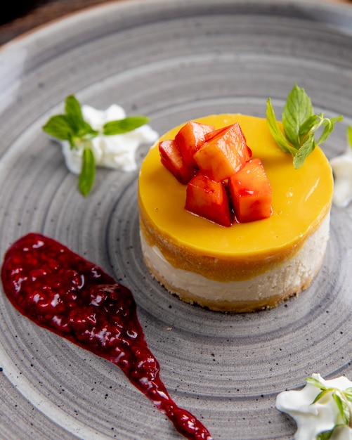 Free photo cheesecake with fruits on top served with berry sauce