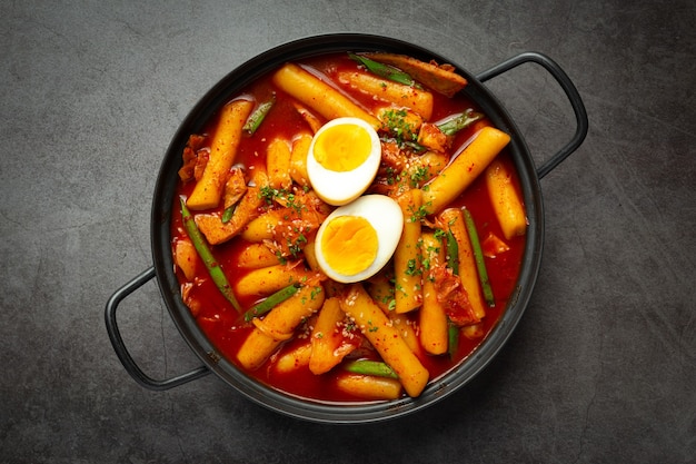 Cheesy Tokbokki korean traditional food on black board background. Lunch dish.