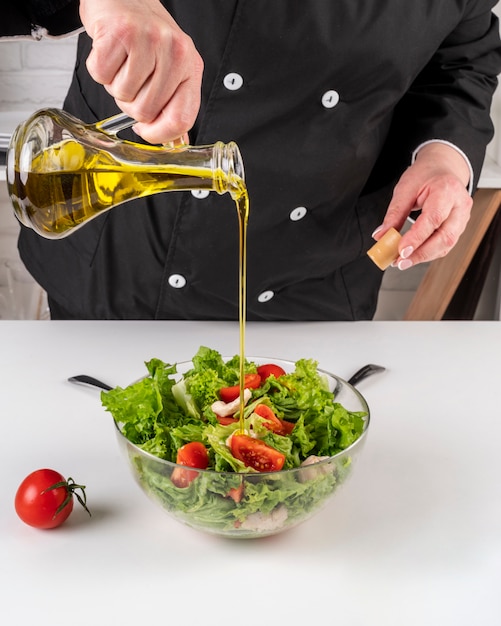 Chef adding oil to salad