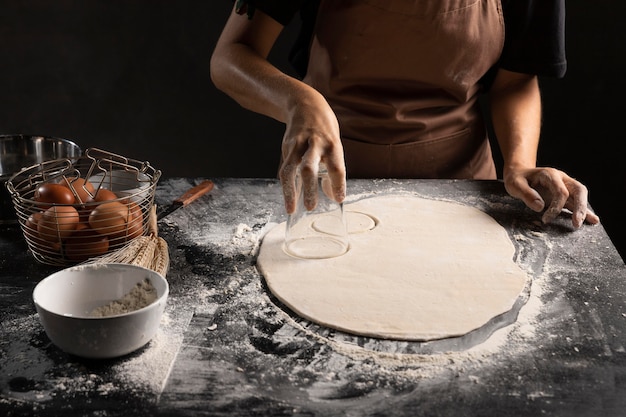 Chef cutting circled out of dough on the table