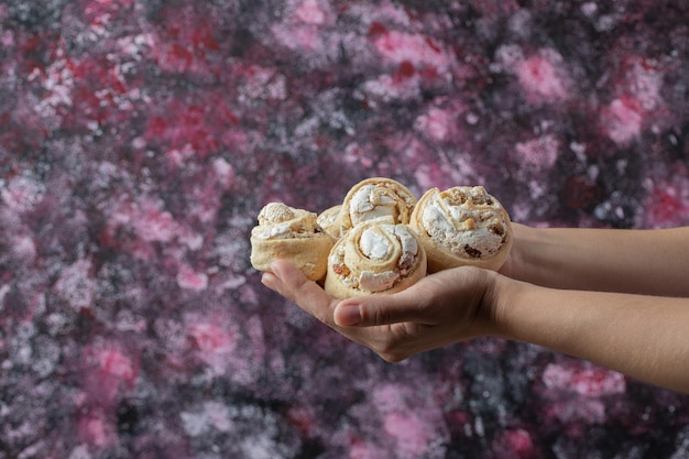 Chef holding crispy cookies with sugar powder in the hand.