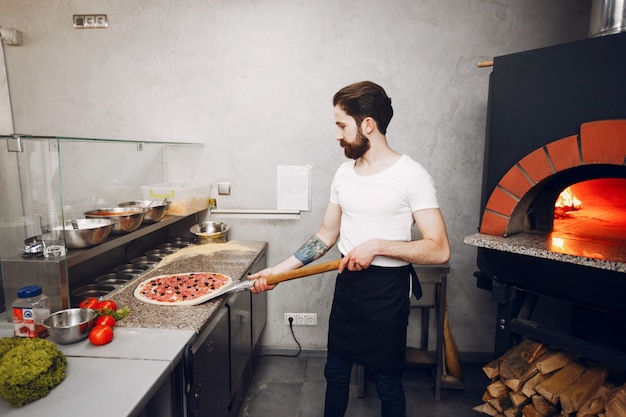 Free photo chef in the kitchen prepares pizza