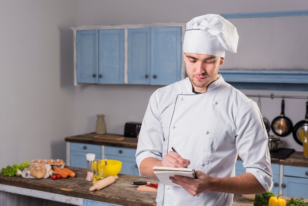 Chef in kitchen taking notes