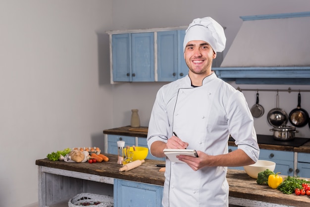 Chef in kitchen taking notes