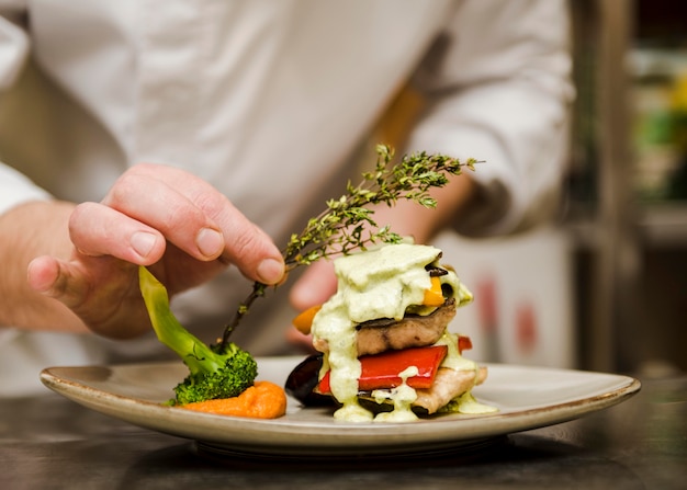 Free Photo chef placing herb on gourmet meal