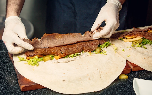 Free photo chef preparing lavash doner with meat and vegetables.