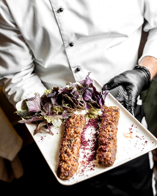 Chef presents a lula kebab served with basil