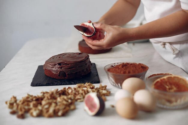 Chef in white clothes prepares a chocolate cake. Lady is preparing dessert. Woman bakes a cake.