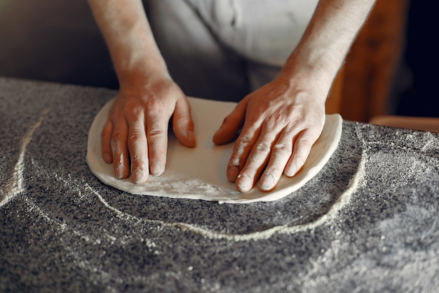 Chef in a white uniform prepare a pizzaa