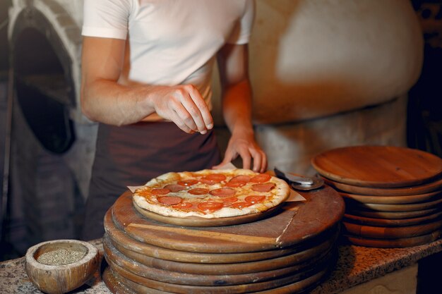 Chef in a white uniform prepare a pizzaa