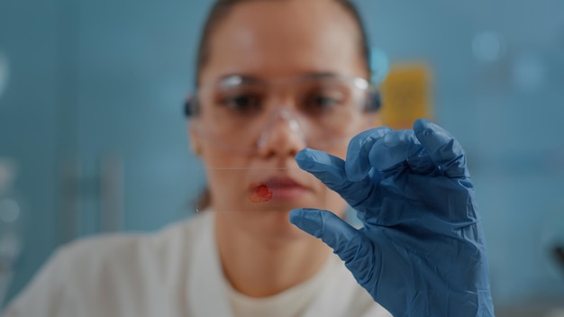 Free Photo chemical specialist holding glass tray with blood sample to analyze molecule and do examination in laboratory. scientist looking at dna substance for biology development in lab. close up