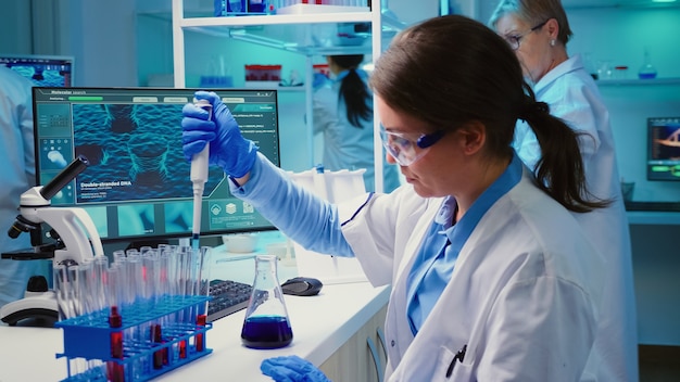 Chemist putting liquid in test tube with micropipette in modern equipped laboratory