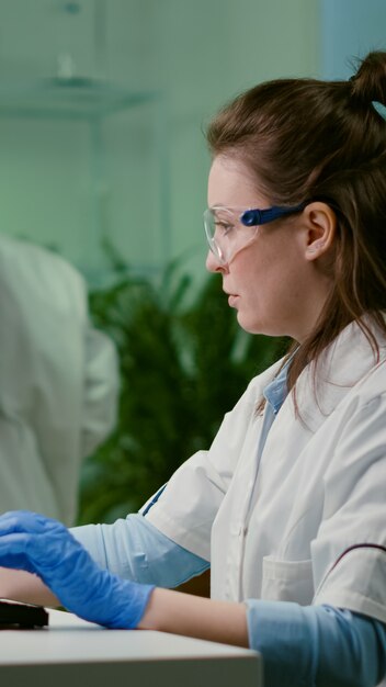 Chemist researcher analyzing test sample putting under microscope for pharmaceutical experiment