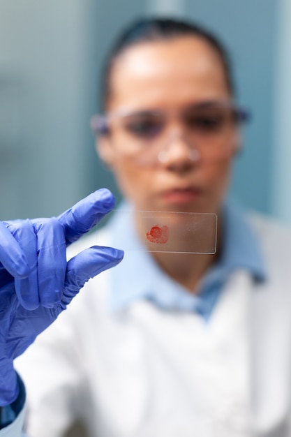 Free Photo chemist researcher holding glass with blood sample working at microbiology experiment