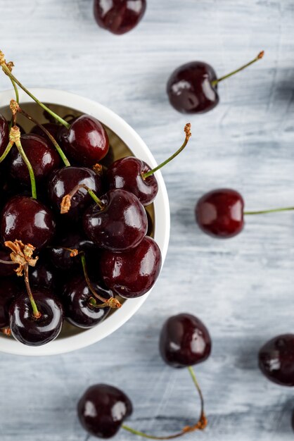 Cherries in a bowl on grunge surface, close-up.