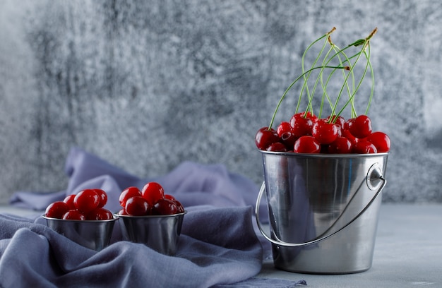 Free photo cherries in buckets with textile side view