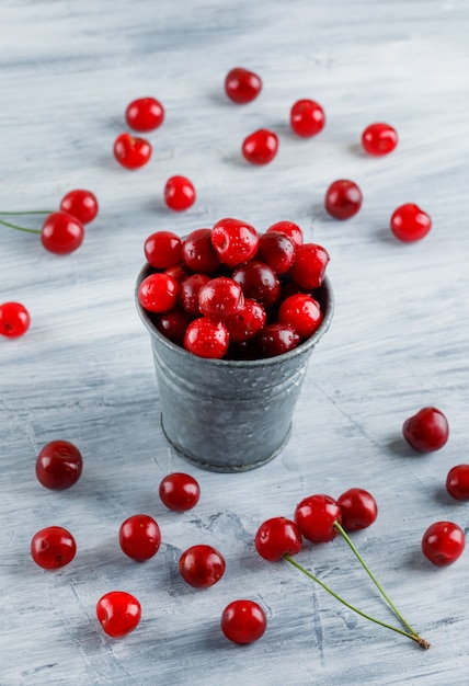 Cherries in a mini bucket high angle view on a grey grunge