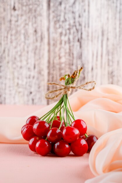 Cherries with textile side view on pink table