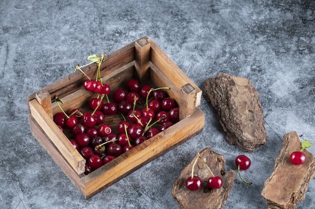 Free photo cherries in a wooden basket on the marble