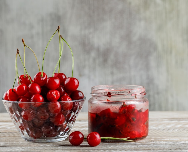 Free photo cherry in a bowl with cherry jam side view on wooden