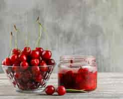 Free photo cherry in a bowl with cherry jam side view on wooden