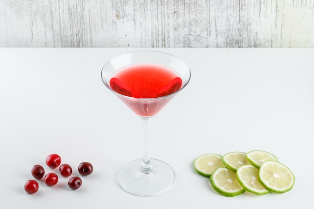 Free photo cherry juice in a glass with cherries, lemon slices high angle view on white