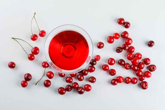 Cherry juice in a glass with cherries top view on a white