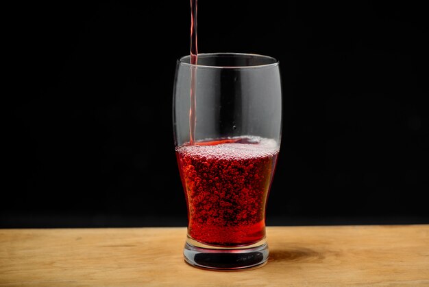 Cherry juice pouring into glass on wooden desk