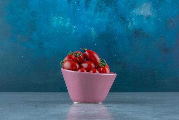 Cherry tomatoes in a cup on blue.