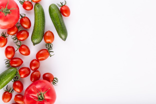 Cherry tomatoes red fresh ripe with red tomatoes and green cucumbers on white background