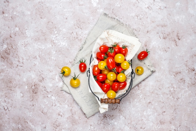 Free photo cherry tomatoes of various colors,yellow and red cherry tomatoes in a basket on light background