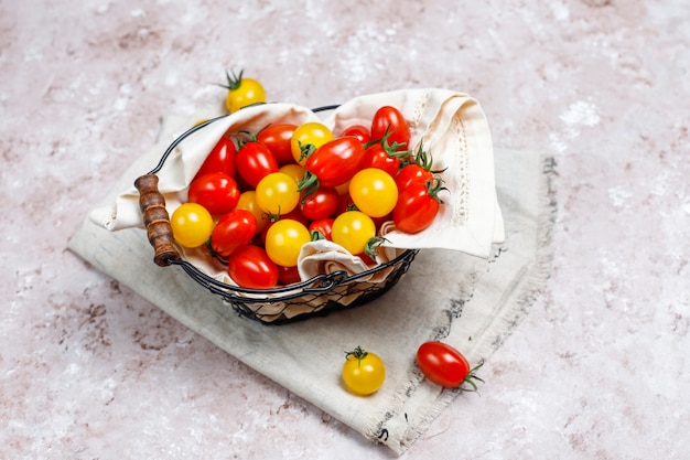 Cherry tomatoes of various colors,yellow and red cherry tomatoes in a basket on light background