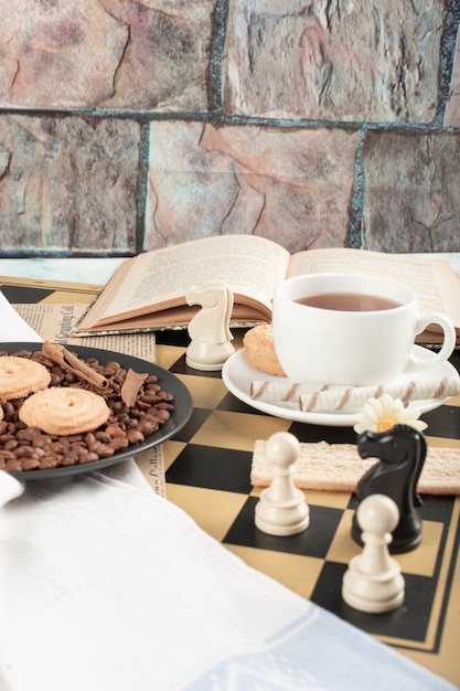 Chess figures, a cup of tea, a book and cookies