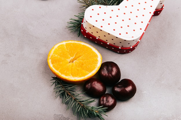 Chestnuts, orange, fir branch and present box on grey floor