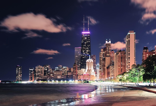 Chicago city urban skyscraper at night at downtown lakefront illuminated with Lake Michigan and water reflection viewed from North Avenue Beach.