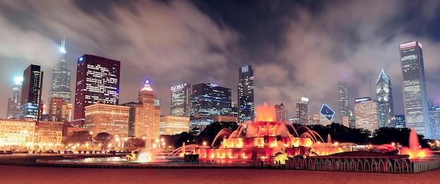 Chicago skyline panorama with skyscrapers and Buckingham fountain in Grant Park at night lit by colorful lights.