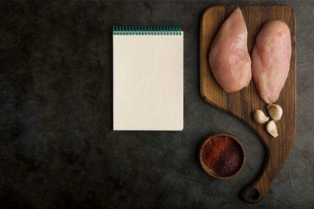 Free photo chicken breast cooking preparation with a cookbook aside