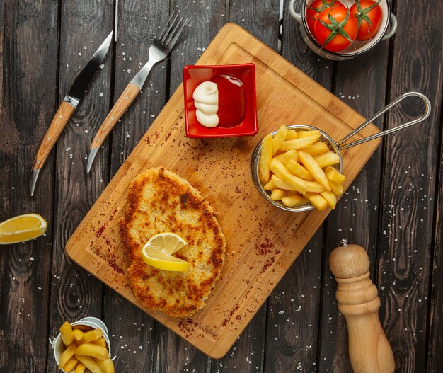 chicken breast patties garnished with lemon, served with fries, mayonnaise and ketchup