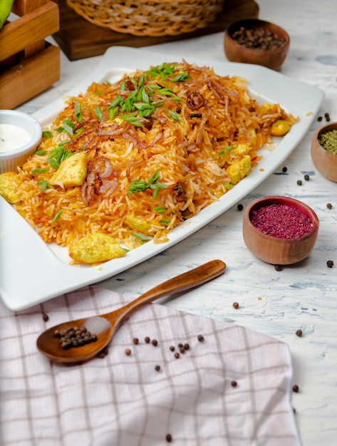 Chicken breast, tomato sauce rice, risotto, plov with herbs , yogurt and sumakh in white plate