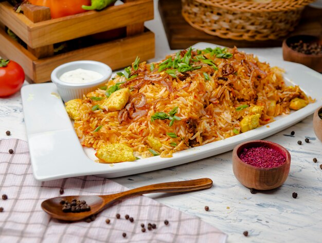 Chicken breast, tomato sauce rice, risotto, plov with herbs , yogurt and sumakh in white plate. 