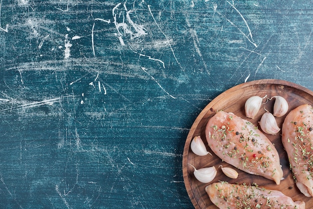 Free photo chicken breast on a wooden board with garlic.