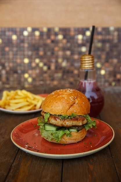 Chicken burger with fresh and pickled cucumber, lettuce and ketchup