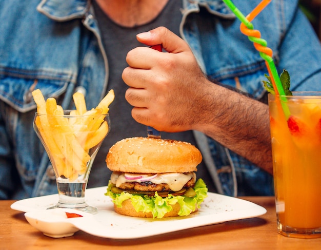 Chicken burger with red onion, melted cheese, pickled cucumber, lettuce, tomato