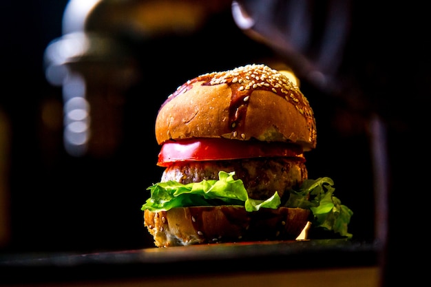 Chicken burger on wooden board tomato lettuce side view