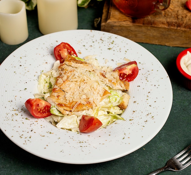 Free photo chicken caesar salad with chopped parmesan, lettuce and tomatoes